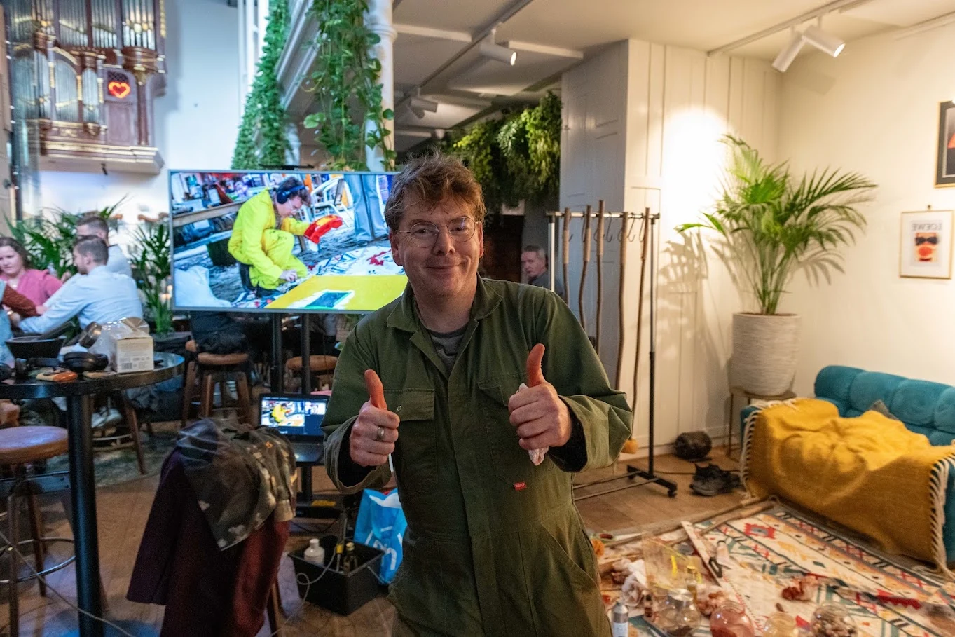 Ward Schepman at an earlier live painting event, with visitors and a colourful artwork behind him.